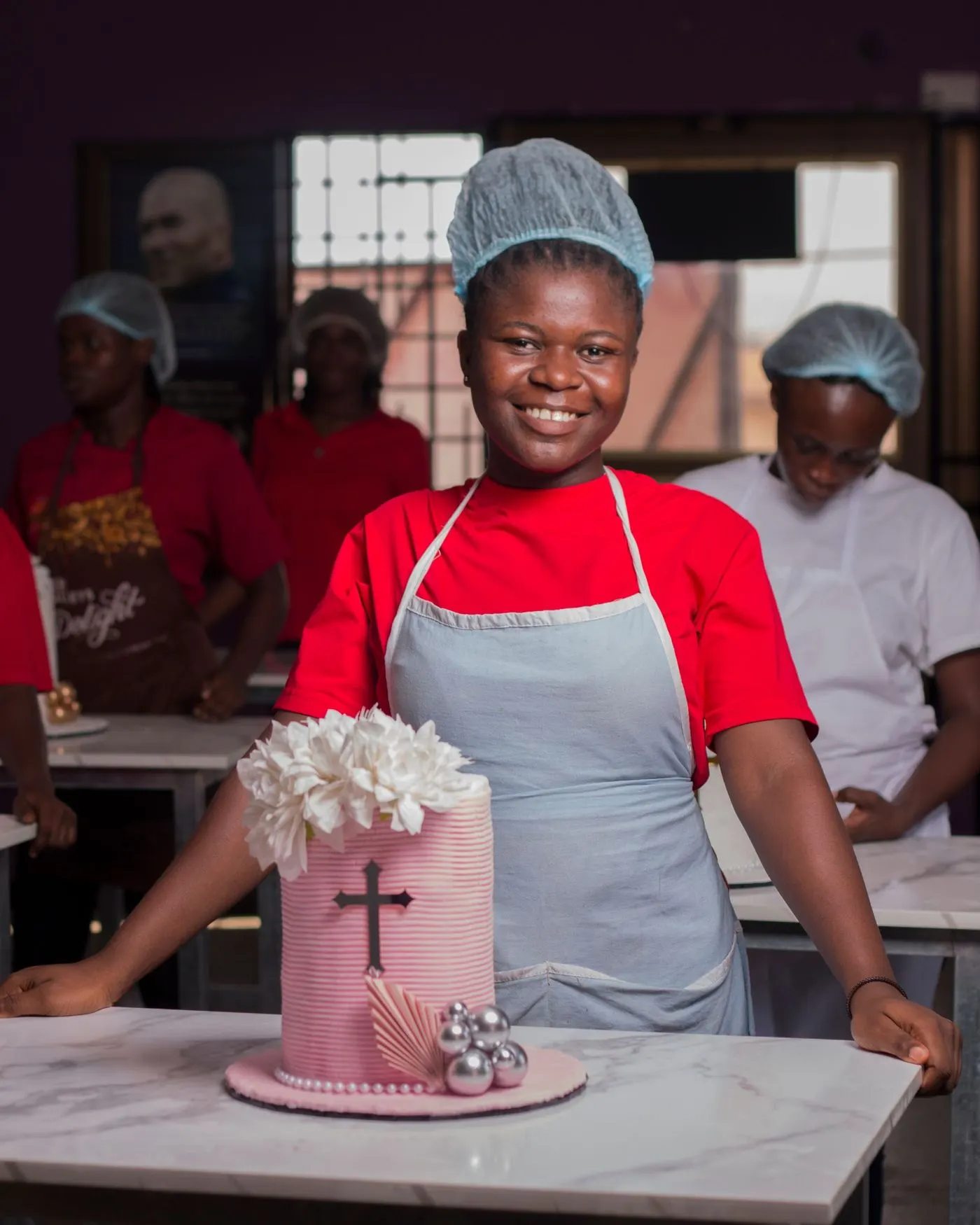 Jeune pâtissière présentant un gâteau décoré dans son atelier