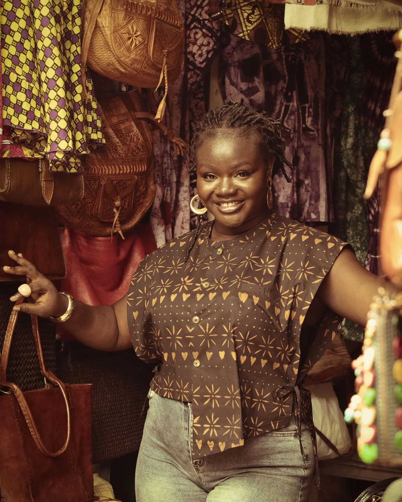 Smiling shopkeeper at her stall of fabrics and accessories